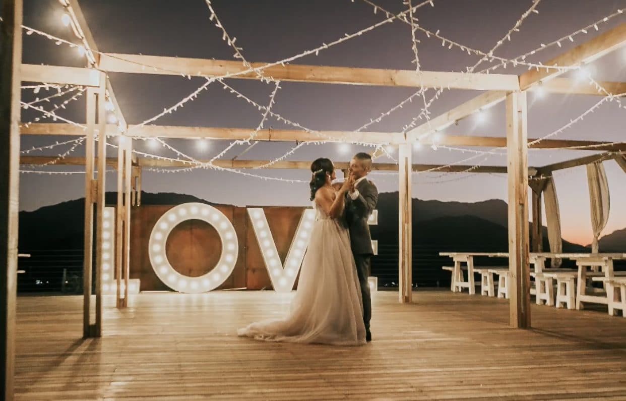 Bride and groom dancing under string lights